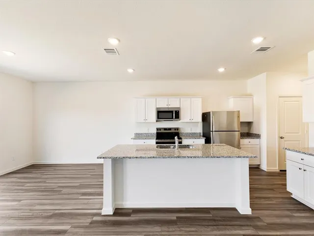 a large white kitchen with kitchen island stainless steel appliances and sink