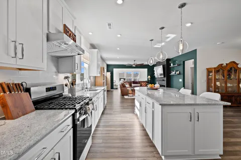 a kitchen with stainless steel appliances a dining table chairs refrigerator and sink