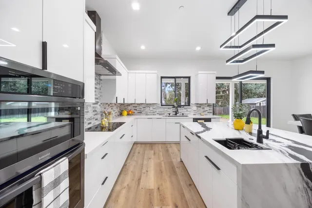 a large white kitchen with a large window and stainless steel appliances