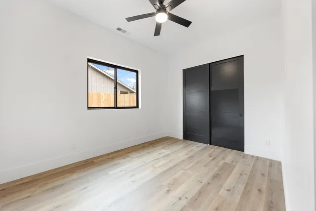 a view of an empty room with window and a ceiling fan
