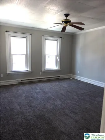 en empty room with windows and chandelier fan