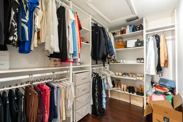a view of walk in closet with clothes and shoes