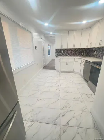 a large white kitchen with stainless steel appliances granite countertop a sink and cabinets