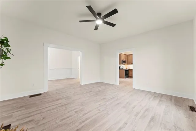 an empty room with wooden floor and ceiling fan