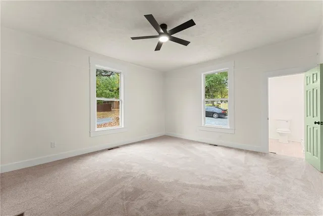 an empty room with windows and ceiling fan