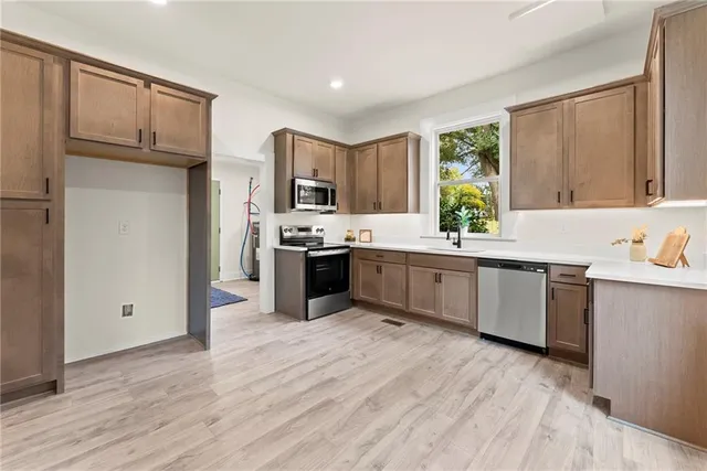 a kitchen with kitchen island granite countertop a sink cabinets and stainless steel appliances