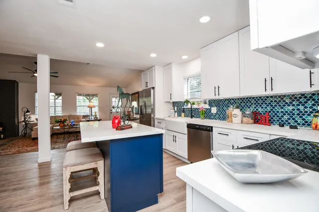 a kitchen with kitchen island granite countertop a sink and white cabinets