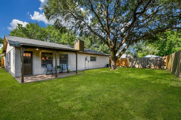 a view of a backyard with table and chairs and a large tree