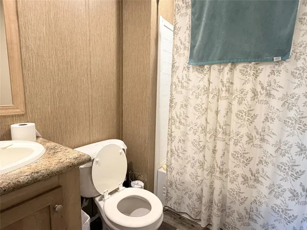 a bathroom with a granite countertop toilet and a sink