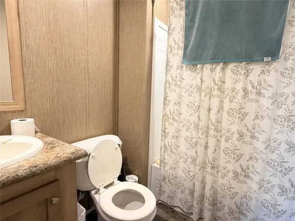 a bathroom with a granite countertop toilet and a sink