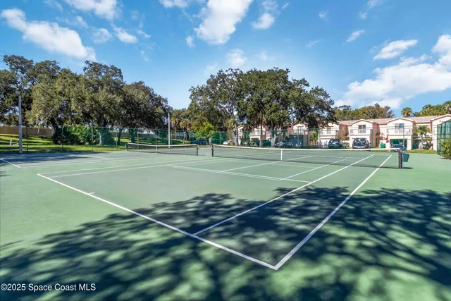 a view of a tennis ground with large trees