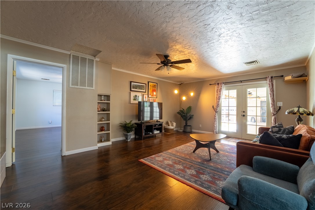 1324 Appaloosa Road Boulder City, NV 89005 - Photo 12 of 42 Rich hardwood floors complement built-in shelving, creating a cozy living space with French doors leading outside.