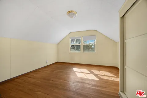 an empty room with wooden floor cabinet and windows