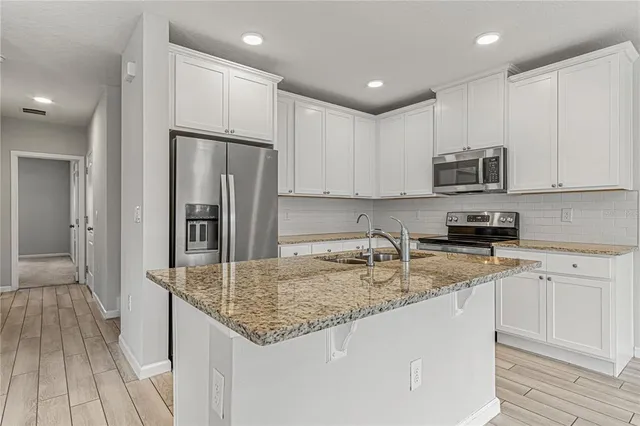 a kitchen with a sink a microwave a refrigerator and cabinets