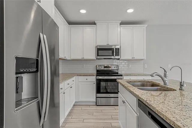 a kitchen with granite countertop a refrigerator stove and sink