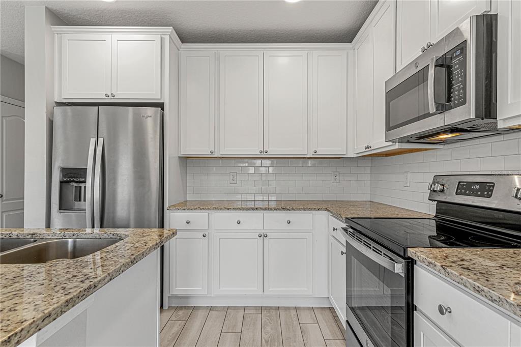 2875 Narcoossee Cmns Way St. Cloud, FL 34771 - Photo 10 of 50 a kitchen with stainless steel appliances granite countertop a sink stove and refrigerator