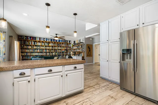 a kitchen with stainless steel appliances granite countertop a refrigerator a oven and white cabinets with wooden floors