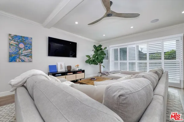 a living room with furniture floor to ceiling window hardwood floor and a flat screen tv
