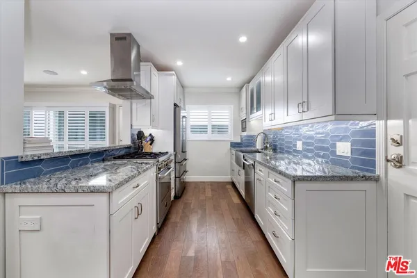 a kitchen with granite countertop kitchen island stainless steel appliances a sink stove and cabinets