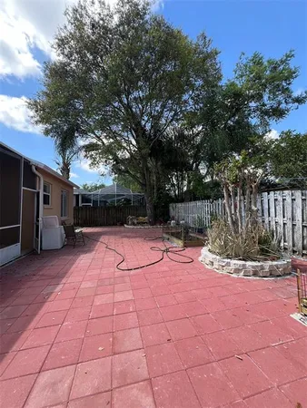 a view of backyard with wooden fence and a large tree