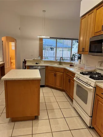 a kitchen with stainless steel appliances a sink a stove a microwave cabinets and a window