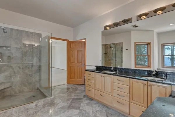 a spacious bathroom with a granite countertop sink mirror and shower
