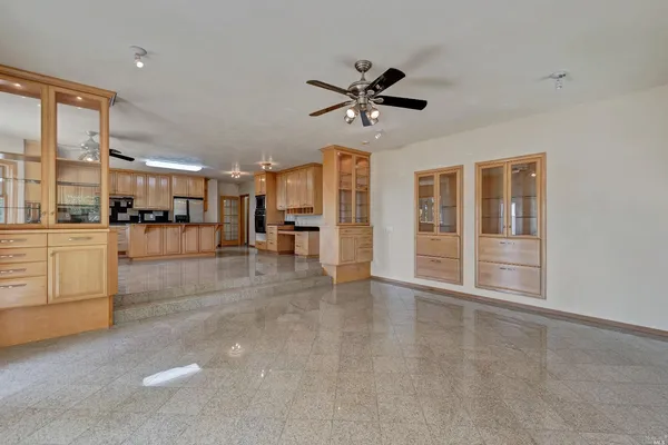 a view of an empty room with kitchen and window