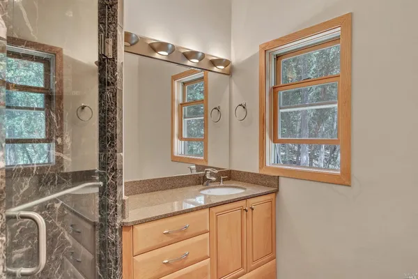 a bathroom with a granite countertop sink a mirror and a shower