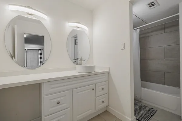 a bathroom with a double vanity sink mirror and bathtub