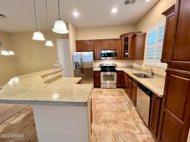 a kitchen with stainless steel appliances granite countertop sink stove refrigerator and microwave