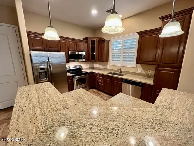 a kitchen with granite countertop a sink stainless steel appliances and cabinets