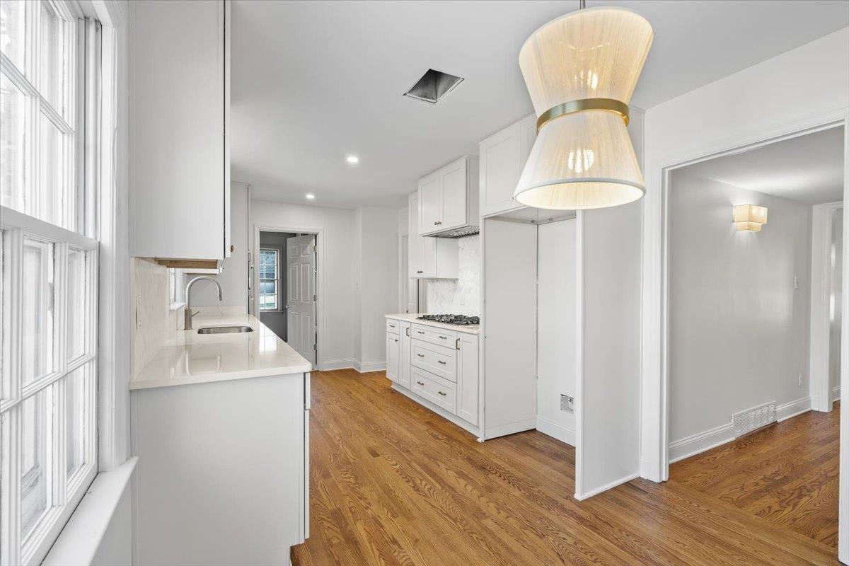 5600 Normandy Road Memphis, TN 38120 - Photo 12 of 28 Kitchen featuring light wood finished floors, visible vents, light countertops, white cabinets, and a sink