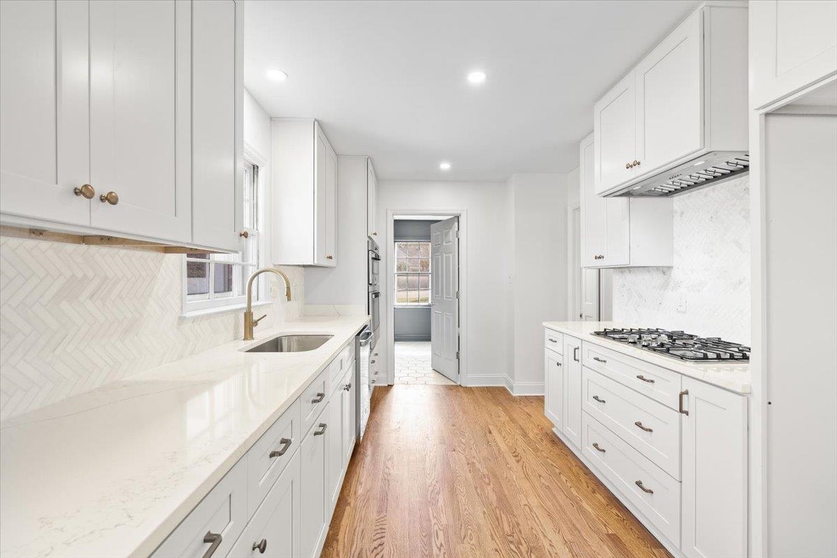 5600 Normandy Road Memphis, TN 38120 - Photo 13 of 28 Kitchen featuring a sink, stainless steel appliances, light stone countertops, and light wood-style floors