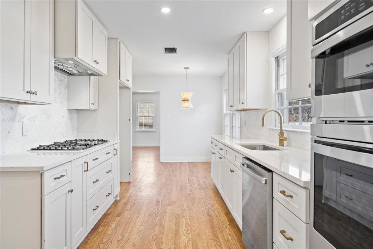 5600 Normandy Road Memphis, TN 38120 - Photo 14 of 28 Kitchen featuring visible vents, appliances with stainless steel finishes, light wood-style floors, white cabinets, and a sink
