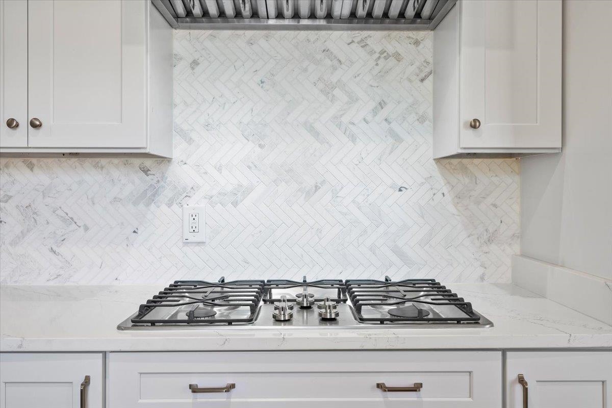 5600 Normandy Road Memphis, TN 38120 - Photo 15 of 28 Kitchen with tasteful backsplash, extractor fan, white cabinets, and stainless steel gas cooktop