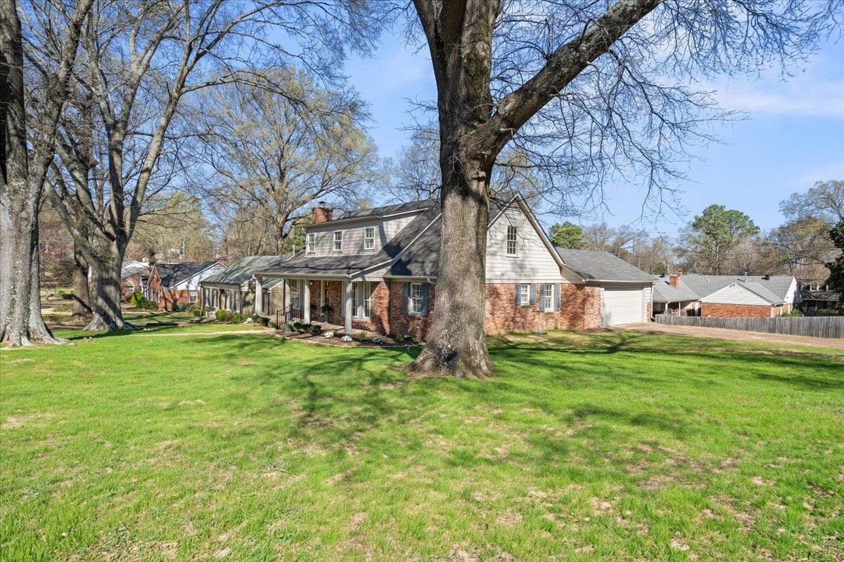 5600 Normandy Road Memphis, TN 38120 - Photo 2 of 28 View of side of home with fence, a yard, a chimney, a garage, and brick siding