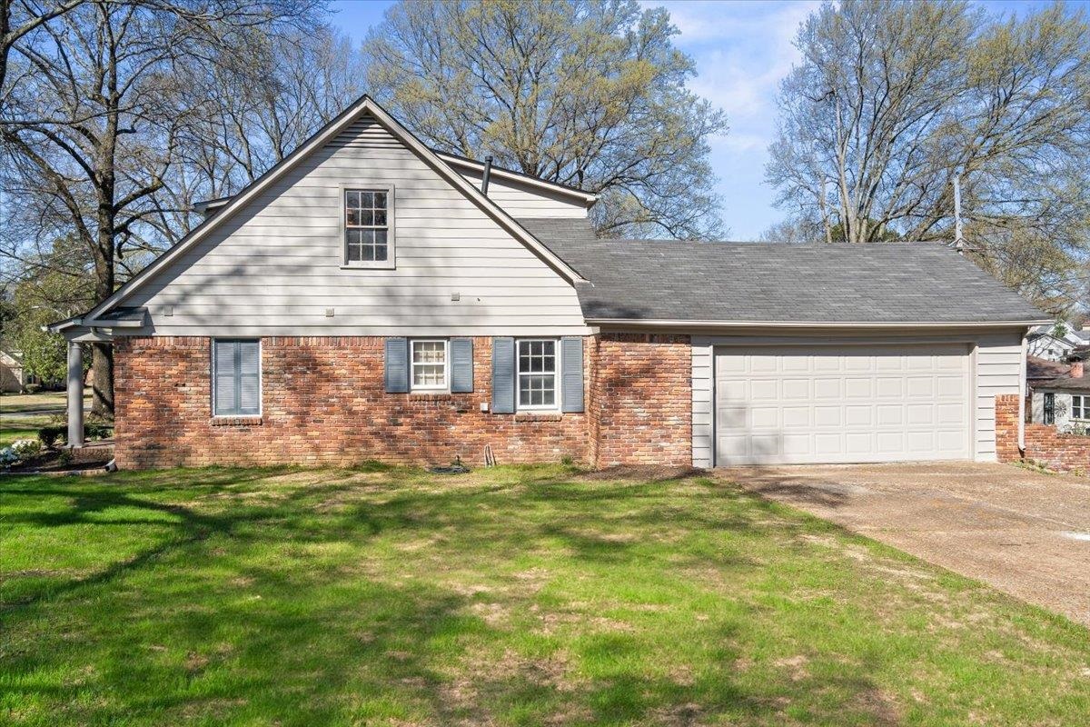 5600 Normandy Road Memphis, TN 38120 - Photo 3 of 28 View of side of property with brick siding, a yard, concrete driveway, and a garage