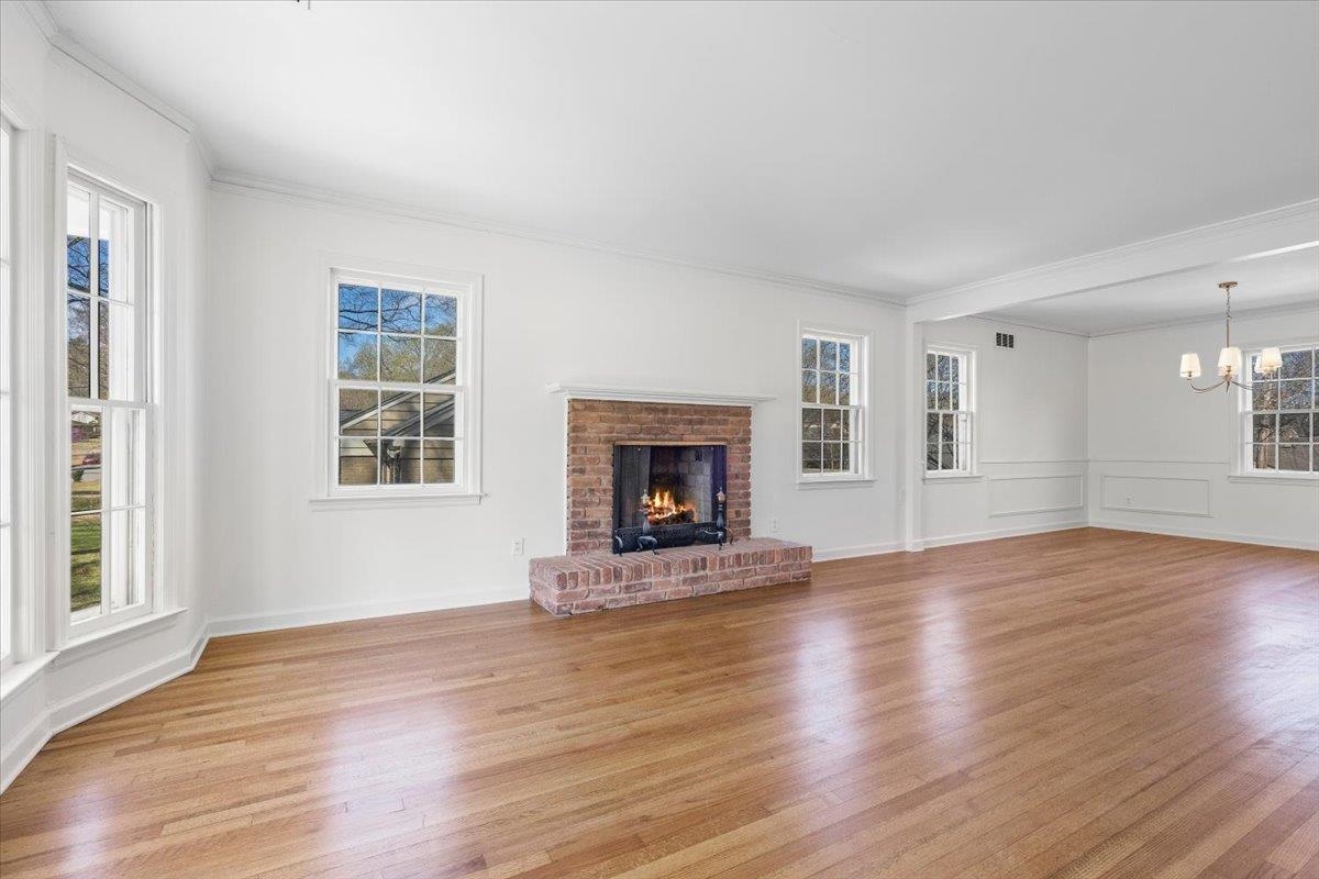 5600 Normandy Road Memphis, TN 38120 - Photo 7 of 28 Unfurnished living room with light wood-style flooring, a brick fireplace, and an inviting chandelier