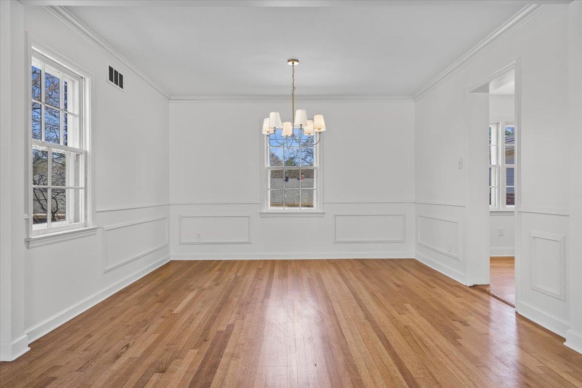 5600 Normandy Road Memphis, TN 38120 - Photo 9 of 28 Unfurnished dining area with visible vents, light wood-style floors, an inviting chandelier, and crown molding