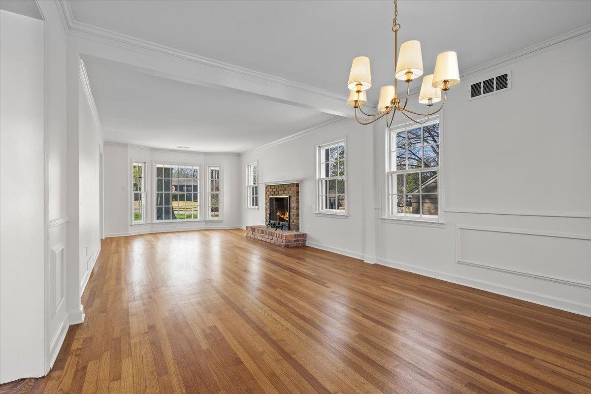 5600 Normandy Road Memphis, TN 38120 - Photo 10 of 28 Unfurnished living room featuring plenty of natural light, wood finished floors, visible vents, and a chandelier