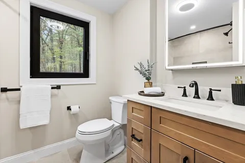 a bathroom with a granite countertop sink mirror vanity and toilet