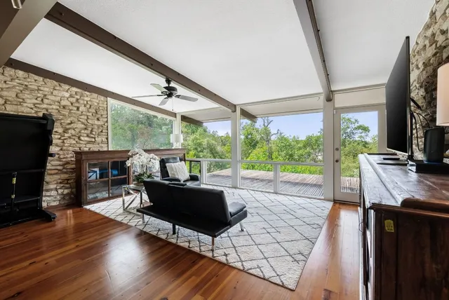 a living room with furniture a fireplace and a floor to ceiling window
