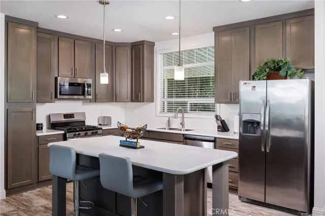 a kitchen with a refrigerator a sink a stove and chairs