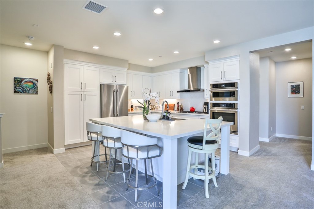 a kitchen with kitchen island a dining table chairs refrigerator and cabinets