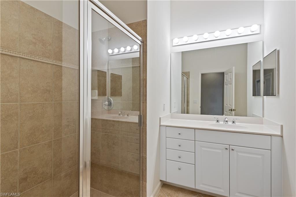 26425 Lucky Stone Road, Unit 201 Bonita Springs, FL 34135 - Photo 16 of 22 a bathroom with a double vanity sink mirror and shower