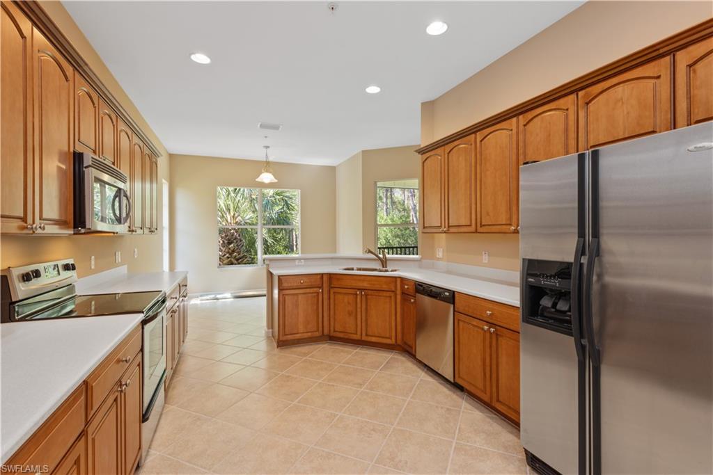 26425 Lucky Stone Road, Unit 201 Bonita Springs, FL 34135 - Photo 5 of 22 a large kitchen with stainless steel appliances granite countertop a refrigerator a sink dishwasher a stove and white cabinets with wooden floor