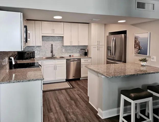 a kitchen with granite countertop kitchen island wooden cabinets and stainless steel appliances