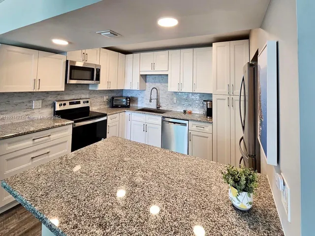 a kitchen with stainless steel appliances granite countertop a refrigerator sink stove microwave and cabinets