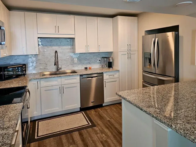 a kitchen with stainless steel appliances granite countertop a refrigerator sink and stove