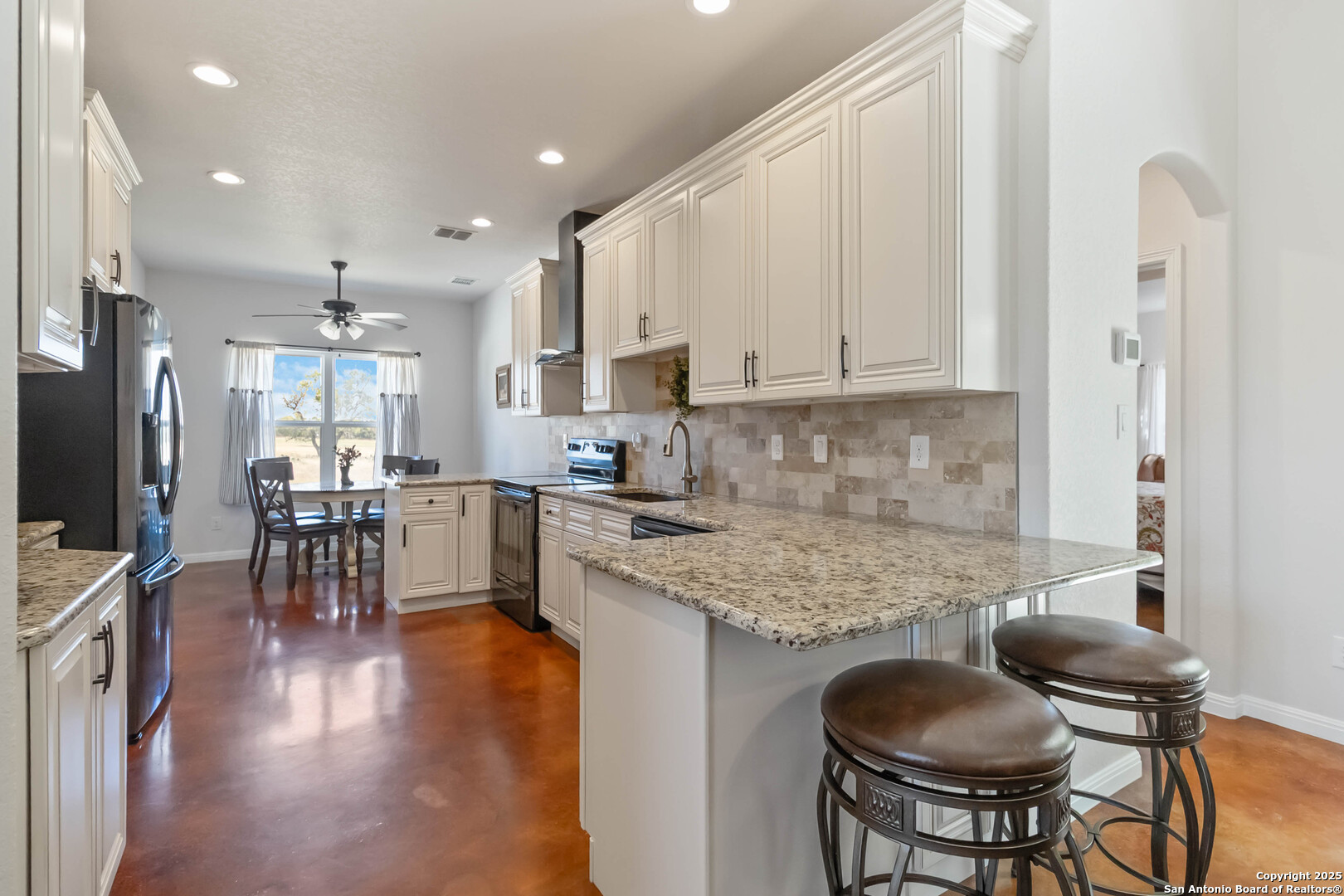 342 Wood View Circle Bandera, TX 78003 - Photo 10 of 45 a kitchen with stainless steel appliances granite countertop a stove top oven a sink a refrigerator with a dining table and chairs with wooden floor